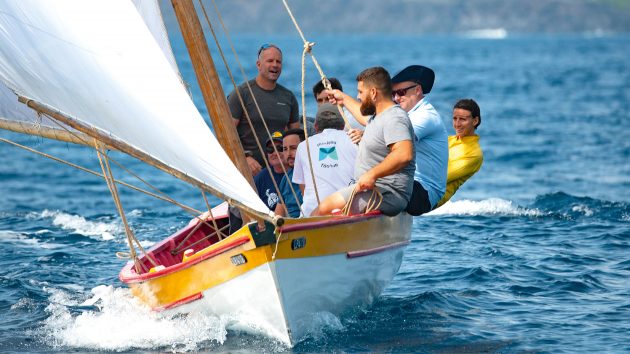 A group of people leaning over the sid eof the boat during a race.