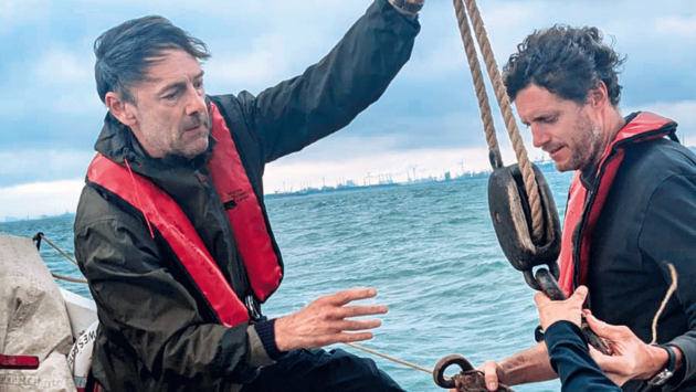 Preparing to hoist a large canvas sail with a traditional block purchase